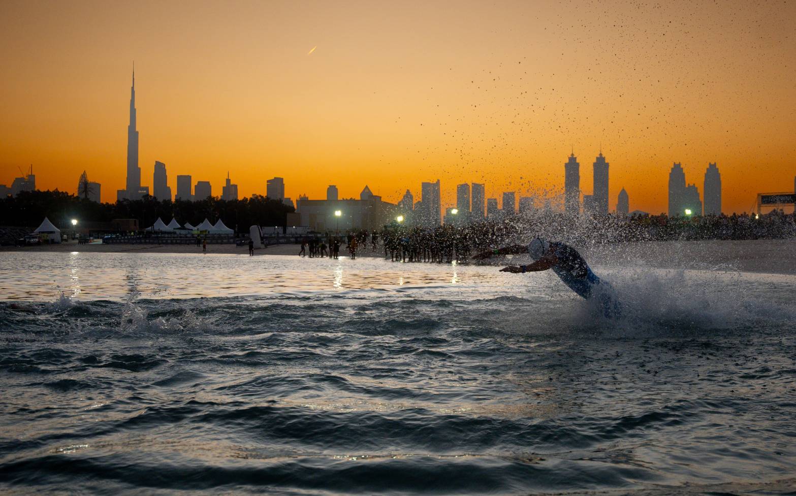 An athlete diving into the water at the start of the Dubai T100 Triathlon
